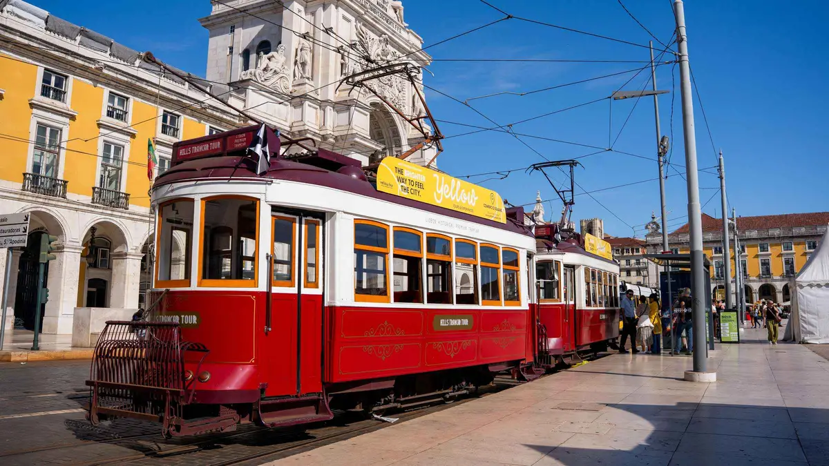 Open-top hop-on hop-off bus passing the Praça do Comércio arch on a 72/96-hour bus, tram and boat ticket in Lisbon